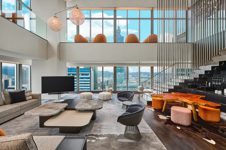 「頂級驚喜套房」坐擁雙層樓逾百坪空間，精選大地暖色調家具、與窗景相襯的湛藍隔屏點綴，呈現成熟化的細膩奢華。業者提供