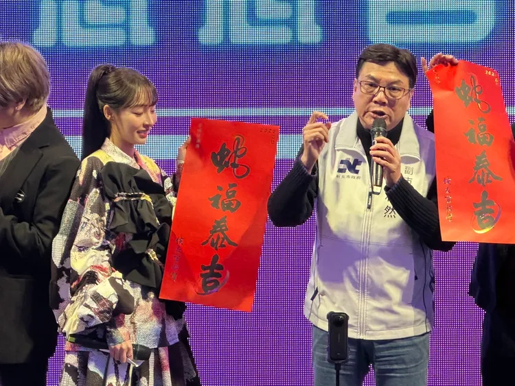 林襄身穿「針織女王」潘怡良所設計服裝，不拿分毫公益主持課照協會尾牙，手持新北「蛇福泰吉」春聯，讓副市長劉和然解說四字涵義。曾佳俊攝