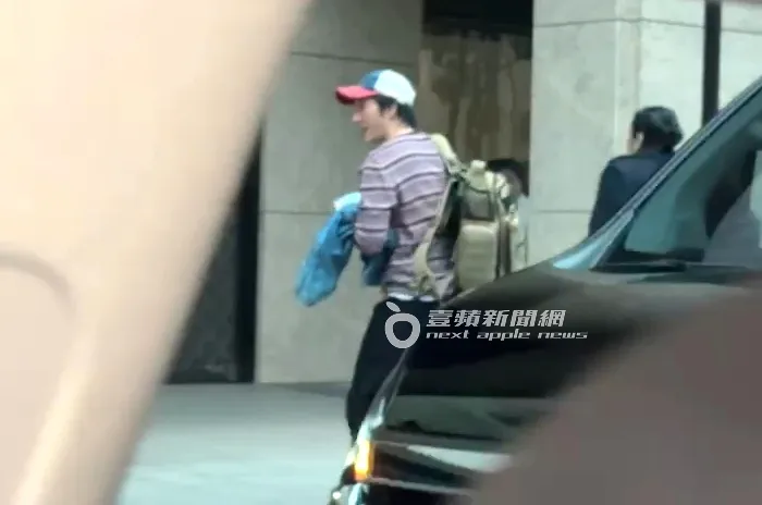 王力宏頭戴紅白藍配色帽，背著行李下車。特勤中心攝