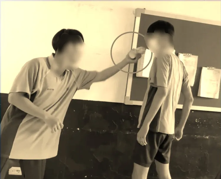 周同學(左)故意塞衛生紙捲挑釁王同學，遭對方用手推開。翻攝畫面