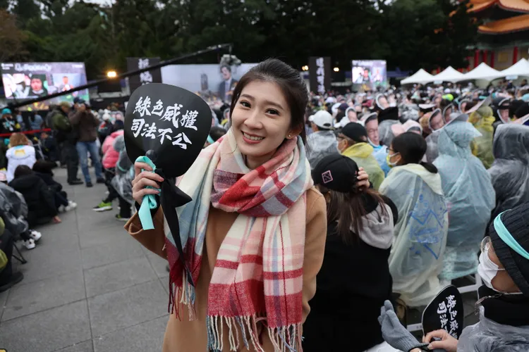 國民黨發言人李明璇手持民眾黨發送的活動標語涼扇。記者李俊毅攝