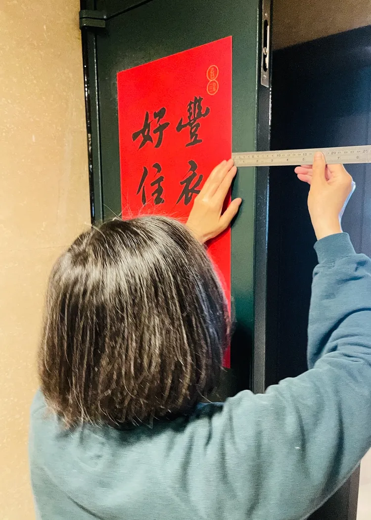拿著尺丈量春聯與門的距離表示，「有人貼春聯跟我一樣，邊邊都要對齊嗎？」。取自蔡英文threads