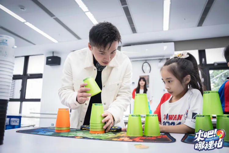 阿緯（左）因經常洗杯子、收玩具而對疊杯有信心，與6歲小老師認真學習。TVBS提供