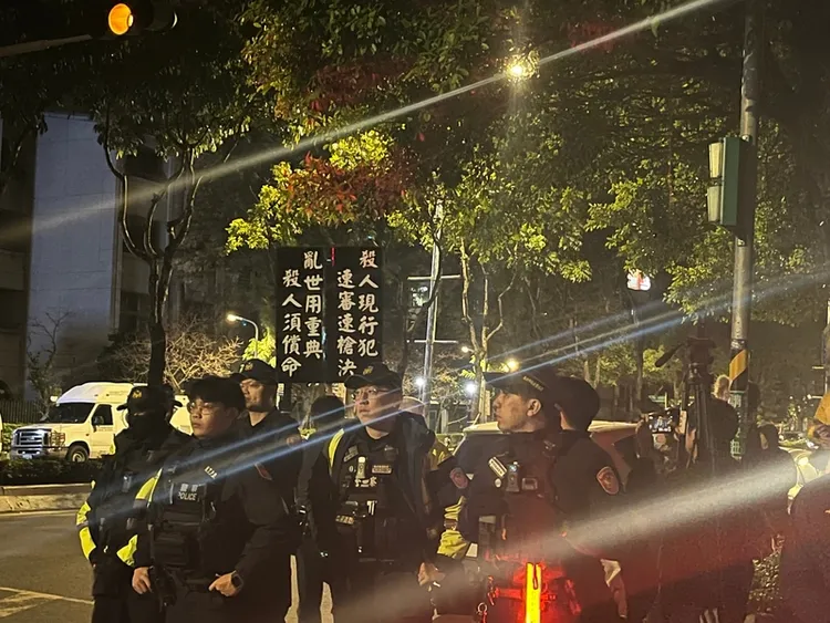 法務部16日晚間10時2分槍決死囚黃麟凱，反廢死民眾（圖）在台北看守所外舉牌表達意見。 中央社