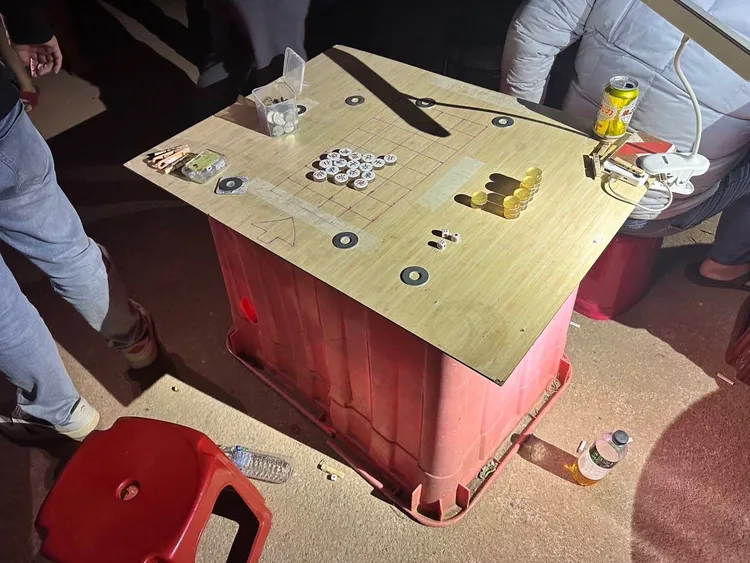 一張桌子與檯燈就能開賭場，眾人就在荒郊祠堂旁玩起「土九」。翻攝畫面