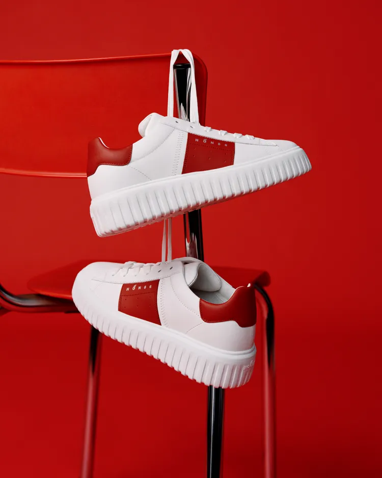 H-Stripes鞋履將牡丹紅色調融入經典純白皮革鞋身，鞋側與鞋尾的紅色拼接貫穿整體設計。品牌提供