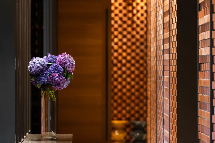 In Between之間餐廳專屬的入口廊道，觸眼所及為紅磚砌牆與燈火絢爛的信義區景致，溫潤的串聯當代與歷史交織的旅程序曲。業者提供