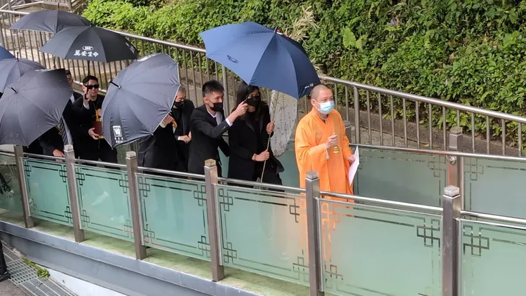 黑衣幫眾一路護著家屬與么么牌位，跟著法師腳步移靈進入館內設置靈堂。翻攝畫面