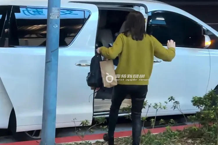 蔡依珊提著紙袋，小心翼翼的踩草地上車。特勤中心攝