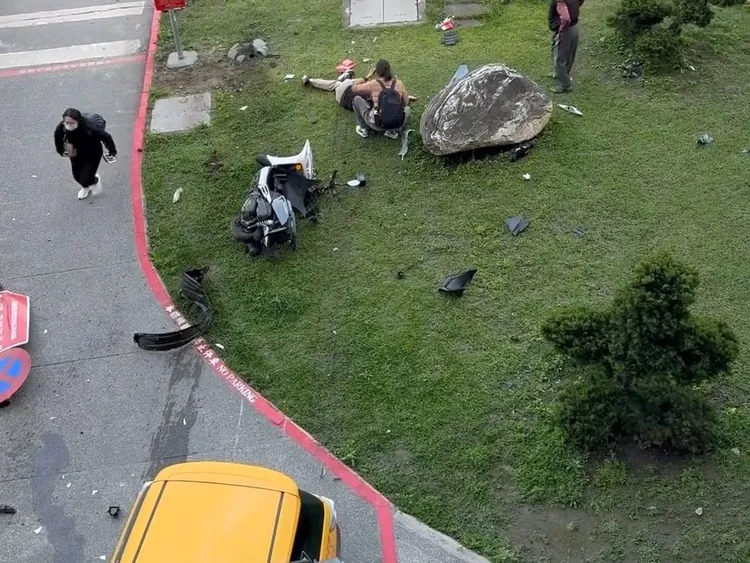 機車騎士被計程車撞倒在◎花圃。翻攝畫面