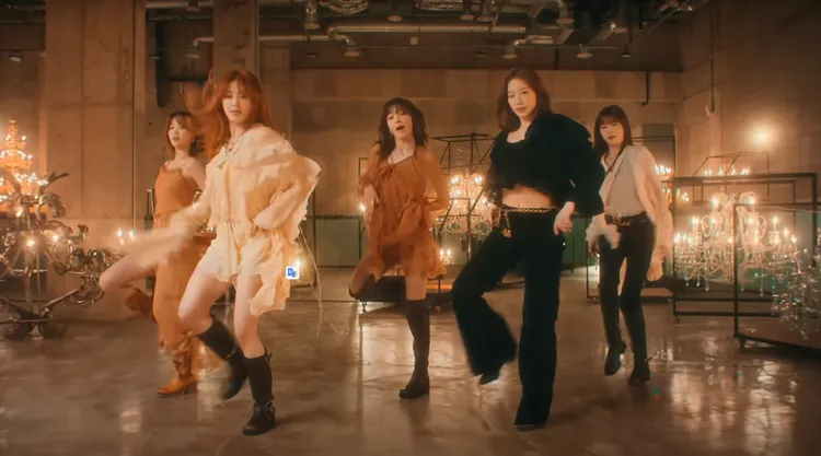 宮脇咲良（中）以橘棕色真絲薄紗荷葉邊斗篷上衣打造唯美風格。翻攝HYBE LABELS Youtube