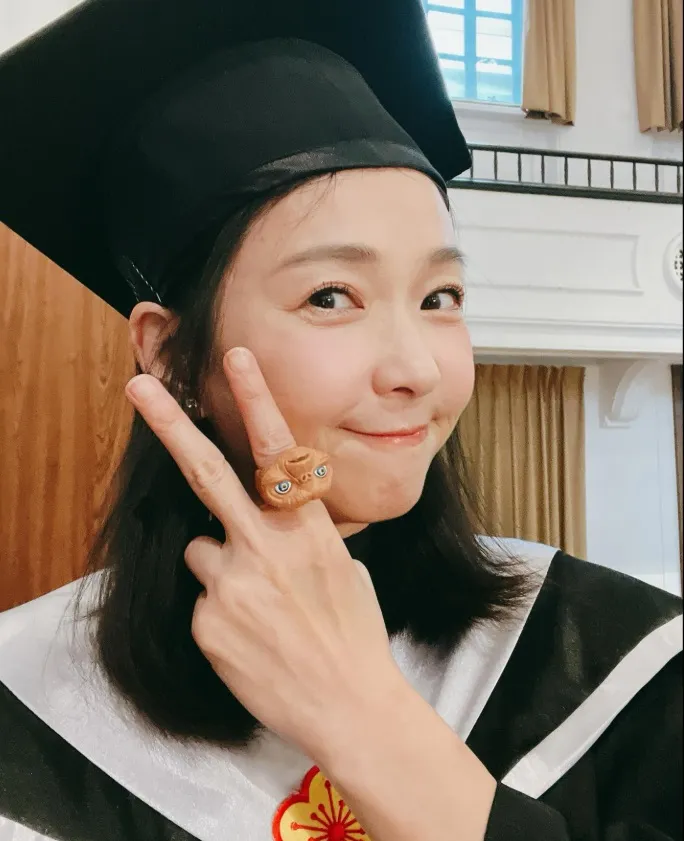 六月穿上碩士服、碩士帽拍照。翻攝六月Threads
