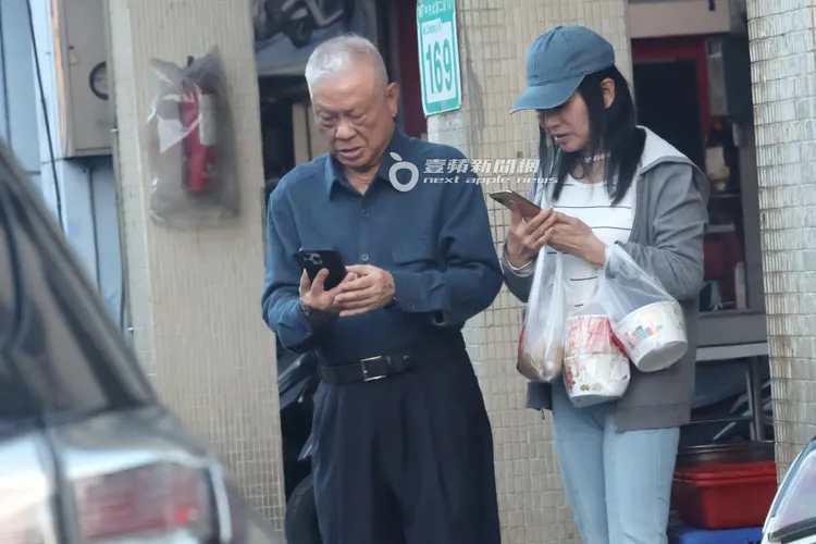 蔣黎麗（右）和富商在店門口滑手機等車。特勤中心攝