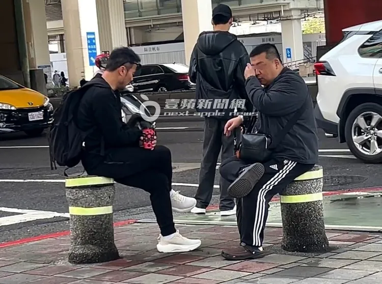 李銘忠（左）趁友人揉眼睛時，抓時間滑手機。特勤中心攝