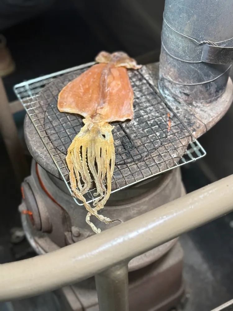 購買後工作人員會將魷魚乾放置於烤爐上烤至微焦，濃郁鹹香的香氣瞬間瀰漫在溫暖的車廂中。S.H.攝