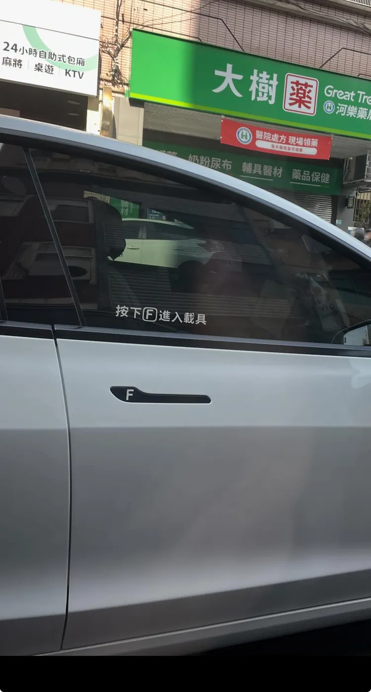 一名網友在路上看見一輛特斯拉車門上貼著「按下『F』進入載具」貼紙。翻攝《路上觀察學院》社團