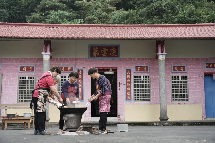 美濃客庄三合院的禾埕，姊妹姑嫂邊閒話家常邊煮著一鍋大封。客家電視台提供