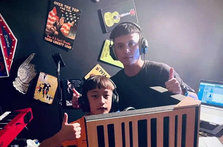 班導兼音樂老師柯孟軒(右)與畢業生瓦旦(左)2021年在錄音室內比讚合影。翻攝畫面