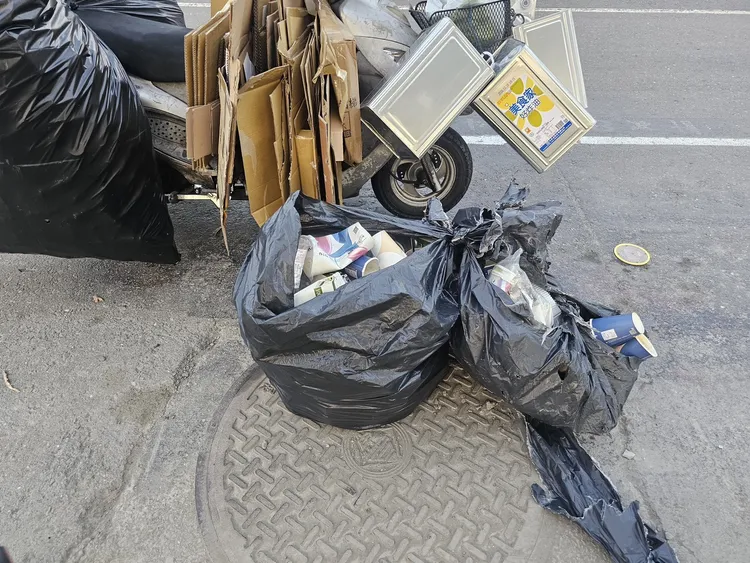 7旬婦騎車載回收物掉滿地，外送員煞車不及摔車。翻攝畫面