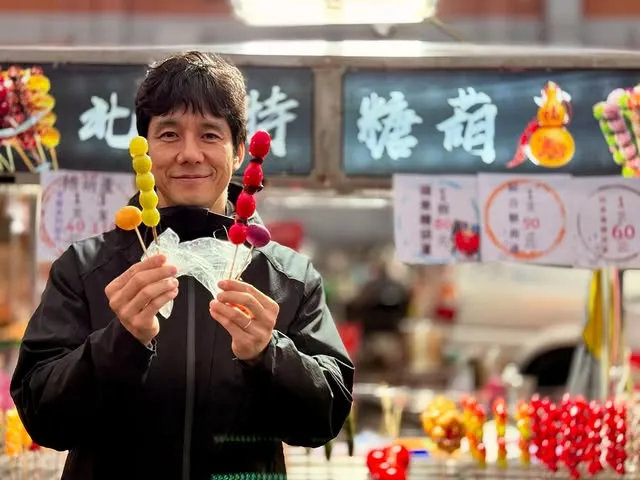 西島秀俊兩手拿著不同種類的水果糖葫蘆，左手無名指上的戒指引人注意。翻攝西島秀俊IG