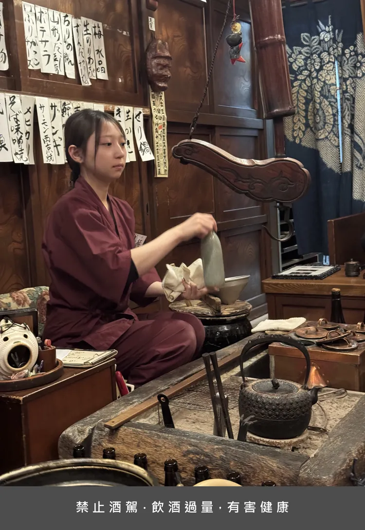 店內服務生在爐邊熱酒（熱燗）由自家酒廠釀製的燒酒溫潤香醇。蘋果妹拍攝