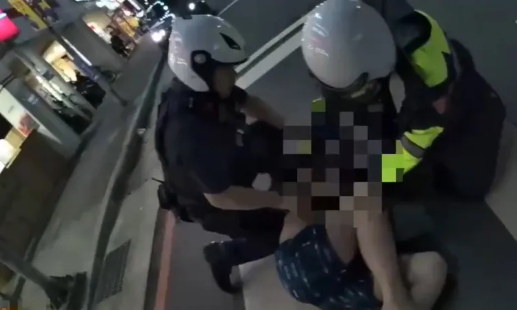 男子遭警方壓制管束，黑狗護主上前咬了警員一口。翻攝畫面