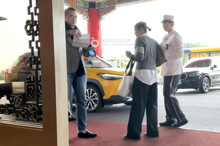 江振誠（左）跟「馬尾妹」一同離開圓山飯店，在飯店門口等計程車，她拿出資料給他簽名。特勤中心攝