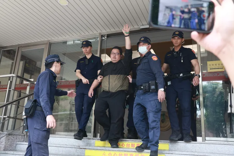 潑漆男子遭帶回警分局時還高舉雙手疑表達自身立場。彭欣偉攝