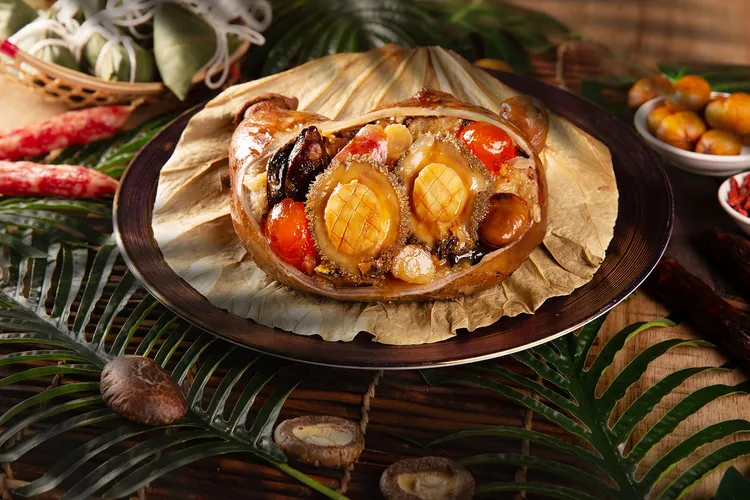 台北萬豪酒店頂級粽禮「鮑魚八寶福袋粽」，嚴選台灣黑毛豬豬肚，包入拌有黑胡椒、花菇、紅蔥酥的糯米，搭配南非鮑魚、碎干貝、栗子、鹹蛋黃等豐富內餡，油炸後再以竹葉與荷葉包裹，以極致上湯蒸煮而成。每顆售價2299元，含精美保冷袋。業者提供