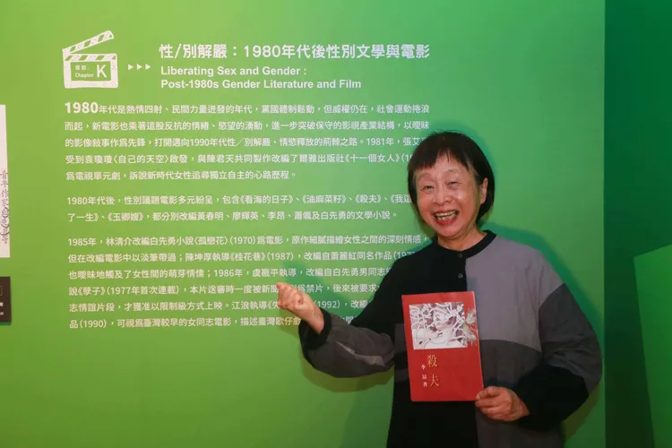 作家李昂手持其著作《殺夫》於展牆前。國立台灣文學館提供