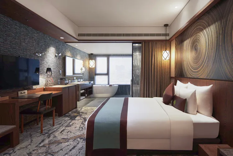 東方禪主題房以「靜、溪流、大木斷面」元素貫穿設計，像是手工雕繪水漣漪圖騰板、魚兒造型的不鏽鋼裝置藝術與年輪圖案木製桌椅，傳遞禪的意境。阿樹國際旅店提供