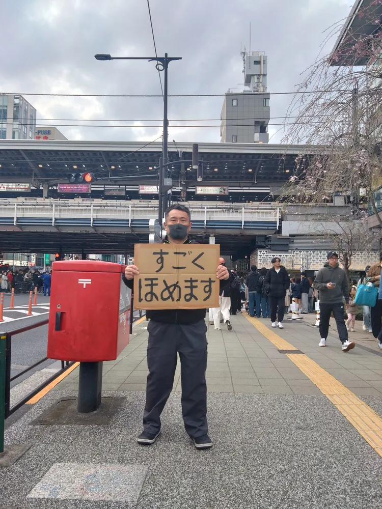 誇獎大叔在街頭舉牌。X誇獎大叔