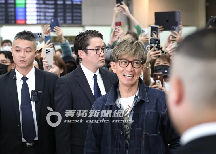 木村拓哉與粉絲合完照，帶著笑臉步出松山機場。特勤中心攝