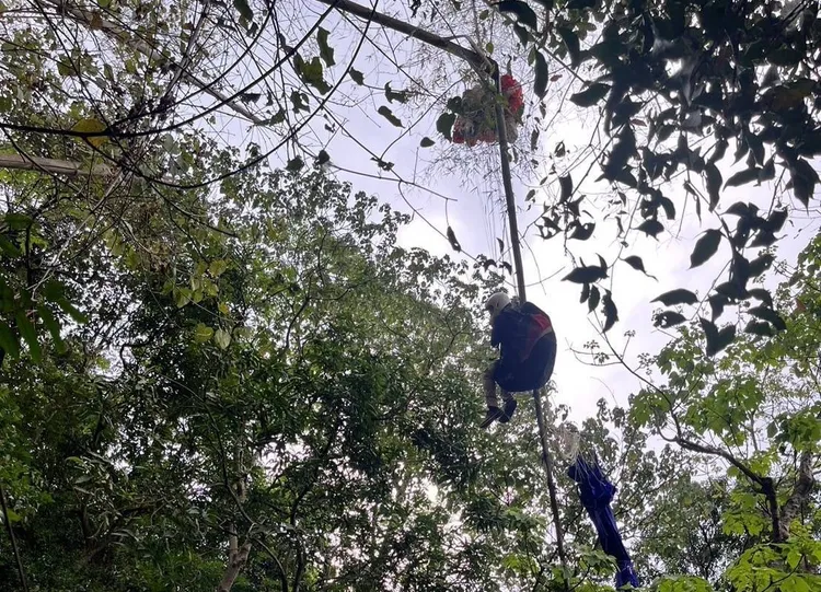 男子卡在樹枝上懸空約10公尺高，下方就是陡峭山坡。民眾提供