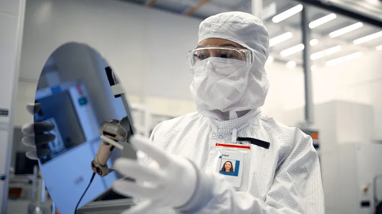 位於美國亞利桑那州錢德勒市的英特爾晶圓廠，一位身穿無塵室裝備的英特爾晶圓代工工程師手持一片矽晶圓。英特爾提供
