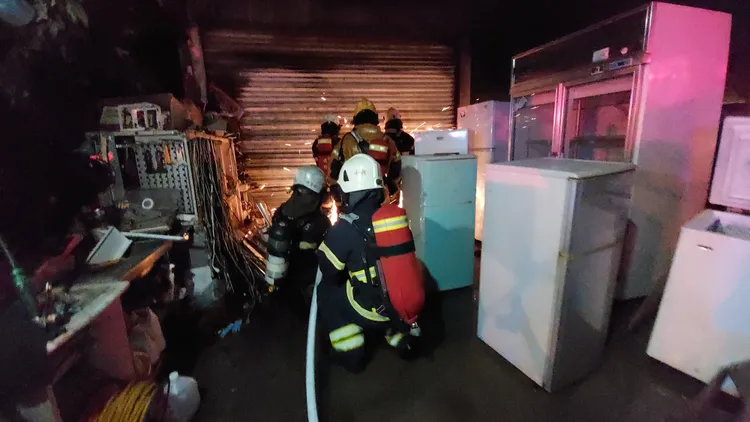 消防人員破壞鐵捲門入內搶救。民眾提供