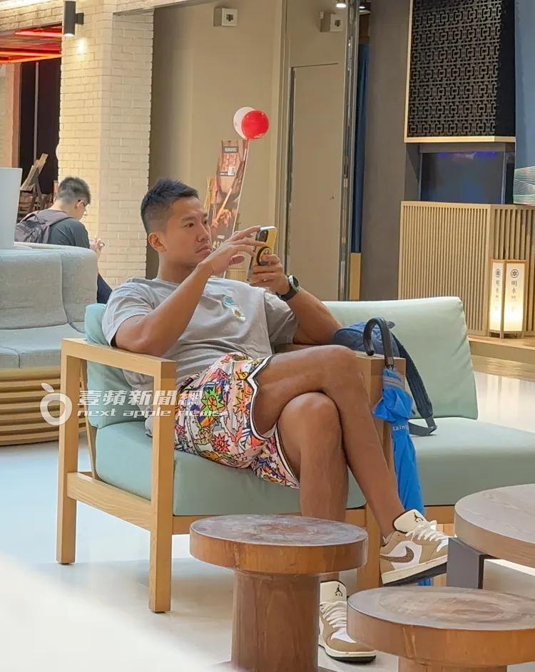 何守正坐在沙發上將手機舉高，認真看著螢幕畫面。特勤中心攝。