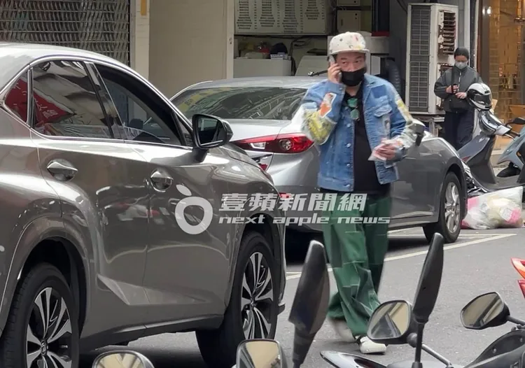 康康手上拿著幾張百元鈔與藥袋，講著電話往車子走去。特勤中心攝