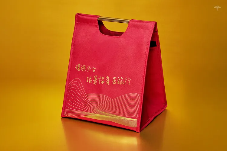 今年全新設計的時尚保冷袋，今年全新設計的時尚保冷袋，以寓意祝福的紅金色系搭配金色線條，呈現台灣山海之美。業者提供