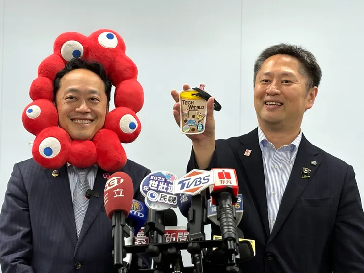 大阪市觀光局萬博促進部長井村悟朗（右）21日秀出參觀Tech World館所獲得的珍珠奶茶造型旅行卡夾。中央社
