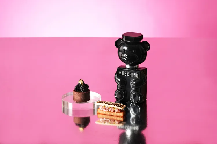 MOSCHINO PARFUM「TOY BOY淡香精」（右）主要為男性打造，「黑莓柑曼怡巧克力塔」（左）猶如一身黑裝的神祕紳士，鹹點「塞拉諾松露薯塔」（中）則以濃郁的荳蔻高湯煨煮後酥炸。業者提供
