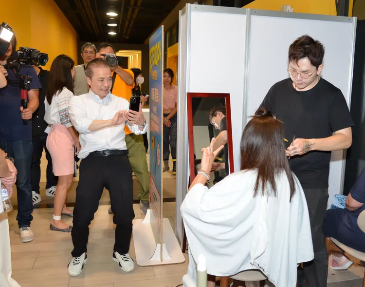 張榮華幫正在剪髮的員工拍照。三立提供