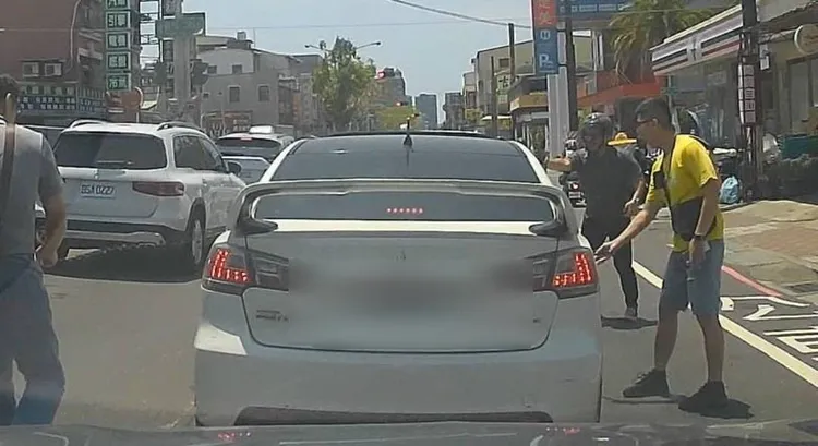 林姓警員（黃衣）破窗控制車輛，手部遭玻璃割傷，經119人員現場包紮，所幸無大礙。翻攝畫面