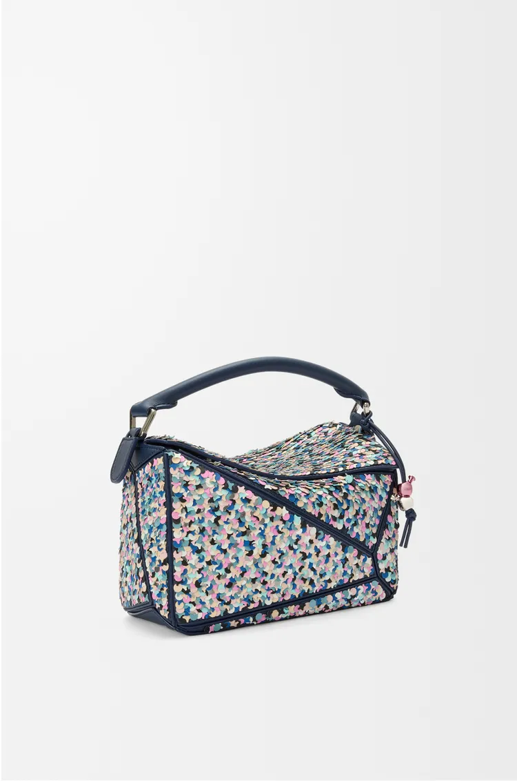 LOEWE 為慶祝 Puzzle 包款十週年，推出全新 Puzzle 10 Confetti 版本，這款設計以手工刺繡的數千塊彩色小皮塊和銀色珠片裝飾包身，呈現歡快繽紛的視覺效果 。品牌提供