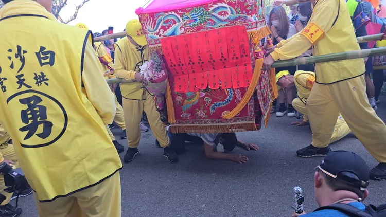 80歲的老先生行動不便，趴在馬路上鑽轎底，鑾轎整整停了1分多鐘。民眾提供