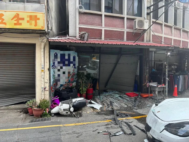 五金行鐵門被撞壞，隔壁的魚店鐵門受損，碎玻璃散落一起，機車也被撞倒。民眾提供