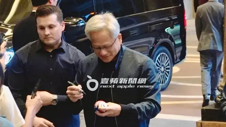 黃仁勳在下榻文華東方酒店外專心幫粉絲簽棒球。特勤中心攝