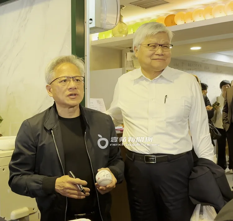 黃仁勳（左）手拿簽完的棒球表示，每次返台的第一晚都是和魏哲家共進晚餐。特勤中心攝