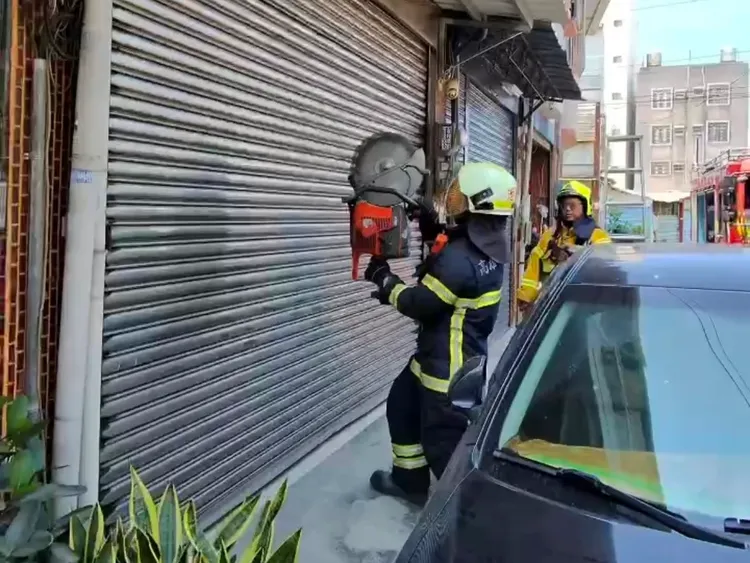 犯嫌關上鐵捲門，警方請消防隊員破門進入。翻攝照片