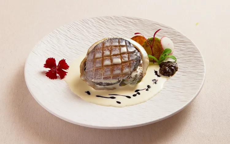 「墨賞新鐵板料理-古亭店」招牌「活鮑魚佐波特酒醬」，選用約180克南非活鮑魚，口感彈牙細膩，完美展現鮑魚與醬汁交融的層次美學。業者提供